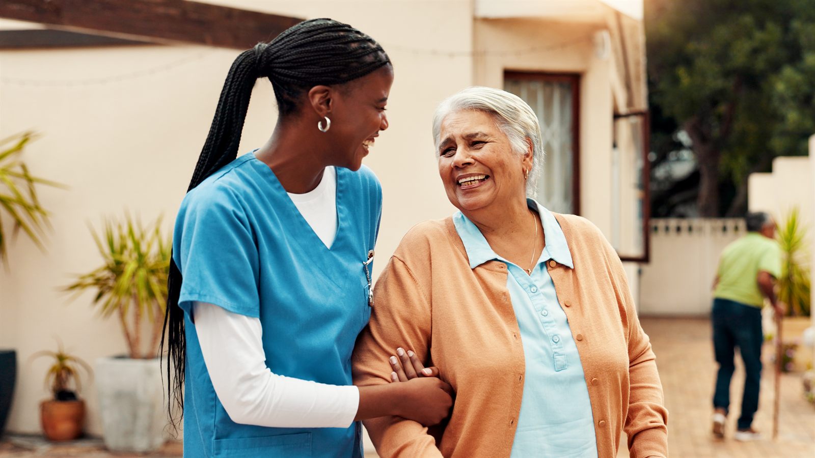 A nurse walking arm-in-arm with a resident outside her facility